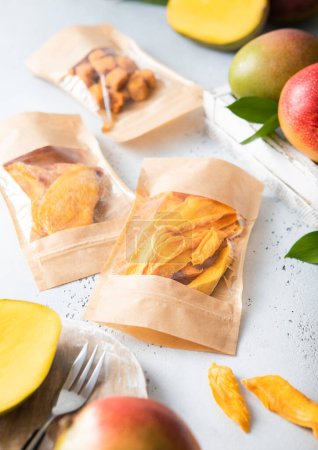 Téléchargez les photos : Emballages simples avec divers morceaux de mangue séchée sucrée avec des fruits frais. - en image libre de droit