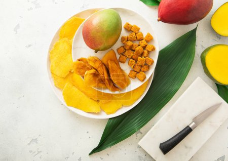 Téléchargez les photos : Assiettes avec des tranches de mangue sucrée séchées et des boules avec couteau et fruits.. - en image libre de droit