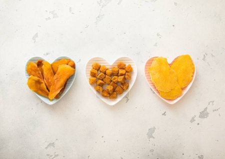 Foto de Rodajas de mango y bolas secas en placas en forma de corazón sobre fondo claro.. - Imagen libre de derechos