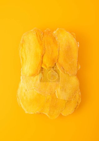 Téléchargez les photos : Grandes tranches de mangue sucrée séchées sur fond jaune. - en image libre de droit