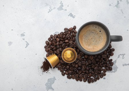 Téléchargez les photos : Tasse à café avec des grains frais et des capsules de café moulues sur fond de cuisine légère.Vue de dessus. - en image libre de droit