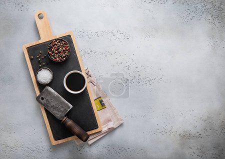 Photo for Meat cleaver on stone cutting board with salt and pepper on light background.Top view. - Royalty Free Image