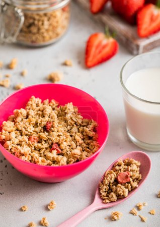 Photo for Granola with strawberry and milk in pink bowl plate on light kitchen background. - Royalty Free Image