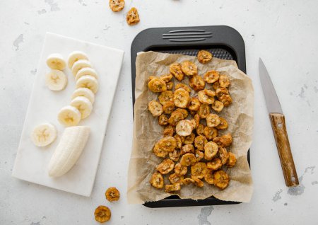 Téléchargez les photos : Plateau de cuisson avec tranches de bananes séchées et bananes pelées crues. - en image libre de droit