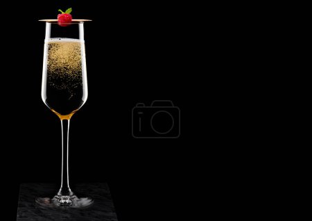 Foto de Elegante copa de champán amarillo con rasspbery en palo sobre tablero de mármol negro sobre fondo negro
. - Imagen libre de derechos