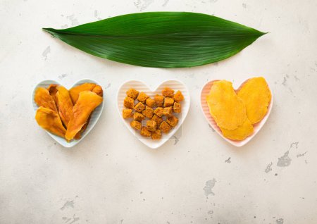 Téléchargez les photos : Tranches de mangue séchées et boules en forme de cœur sur fond clair. - en image libre de droit