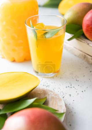 Photo for Fresh mango juice and glass with ice cubes and fresh raw fruits and bottle. - Royalty Free Image