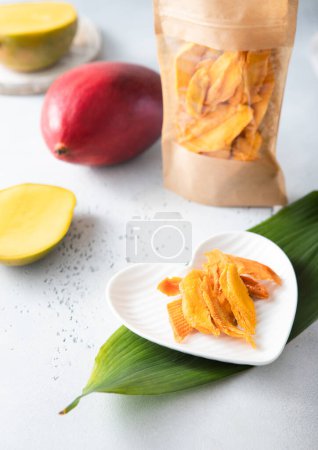 Téléchargez les photos : Mangue séchée en forme de coeur assiette blanche et fruits frais - en image libre de droit