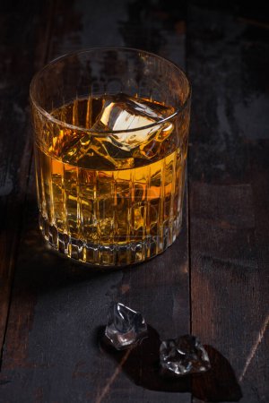 Foto de Whisky escocés de malta simple en cristal con cubitos de hielo sobre fondo de mesa de madera. Vista superior - Imagen libre de derechos