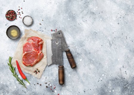 Téléchargez les photos : Filet de côtes de boeuf crues steak sur avec coupe-viande, sel et poivre sur fond de table de cuisine léger.Vue du dessus. - en image libre de droit