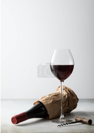 Téléchargez les photos : Sac en papier avec bouteille de vin rouge et tire-bouchon avec verre de vin sur panneau lumineux - en image libre de droit