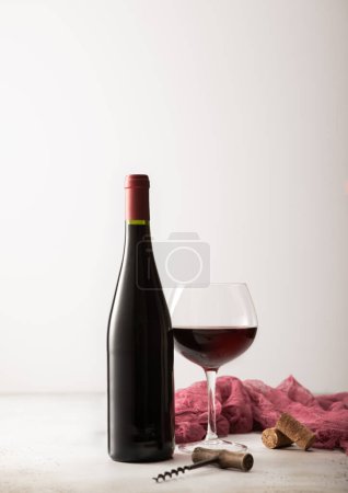 Téléchargez les photos : Verre et bouteille de vin rouge avec serviette rouge et tire-bouchon sur panneau lumineux. - en image libre de droit