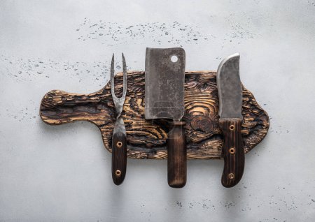 Photo for Wooden chopping board with meat hatchet and fork and knife on light background.Top view. - Royalty Free Image
