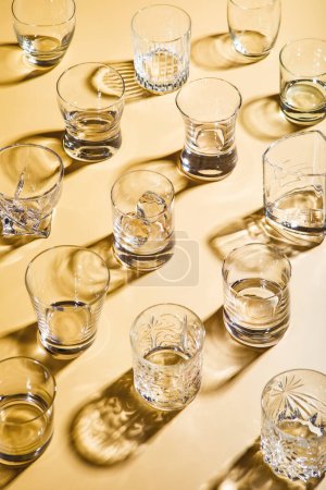 Photo for Various empty whiskey glasses on golden background. - Royalty Free Image