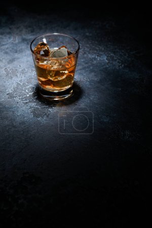Photo for Whiskey glass with ice cubes in middle of black background. Top view. - Royalty Free Image