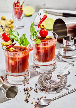 Téléchargez les photos : Verres de vodka Mary sanglante et mélange de jus de tomate avec des ustensiles de cocktail sur panneau lumineux. - en image libre de droit
