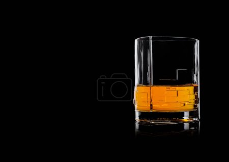 Photo for Scotch whiskey in crystal modern glass on black background with reflection. Space for text - Royalty Free Image