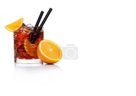Téléchargez les photos : Negroni Cocktail in crystal glass with ice cubes and orange slices with straw and half of fresh orange on white background with reflection. Space for text - en image libre de droit