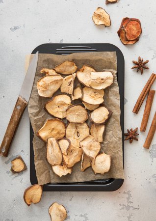 Photo for Dried pear slices on baking tray with cinnamon on light table. - Royalty Free Image