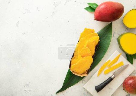 Photo for Dried sweet mangoes with leaf and marble cutting board with fresh fruits. - Royalty Free Image