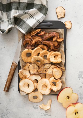 Foto de Surtido de manzanas dulces secas en bandeja para hornear con cuchillo y toalla de cocina. - Imagen libre de derechos
