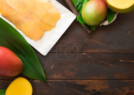 Téléchargez les photos : Lot de grandes mangues séchées sur planche de bois avec des fruits frais crus.. - en image libre de droit