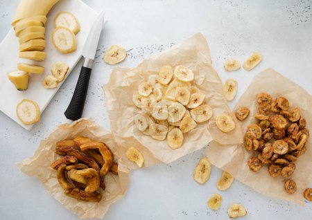 Téléchargez les photos : Diverses tranches de banane croquantes et moelleuses et casse-croûte aux bananes crues et au couteau.Vue de dessus. - en image libre de droit