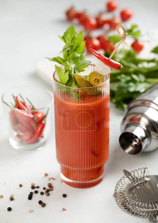 Téléchargez les photos : Cocktail de vodka Mary sanglante et mélange de jus avec des poivrons et du céleri sur un plateau léger. - en image libre de droit