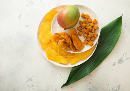 Téléchargez les photos : Assiettes avec des tranches de mangue sucrée séchées et des boules de mangue juteuse fraîche et de feuilles vertes. - en image libre de droit
