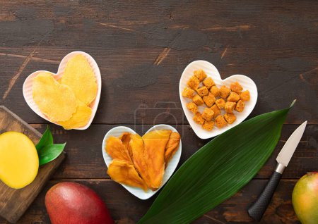 Téléchargez les photos : Tranches de mangue séchées et boules en forme de cœur sur fond en bois.. - en image libre de droit