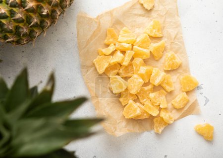 Photo for Yellow organic dried sweet pineapple slices on baking paper on light table. - Royalty Free Image