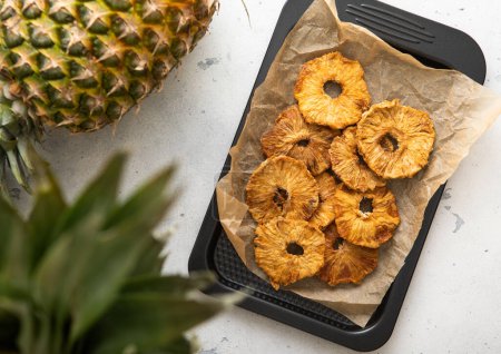 Photo for Organic sweet pineapple circle slices on in baking tray with ripe pineapple on light table. - Royalty Free Image