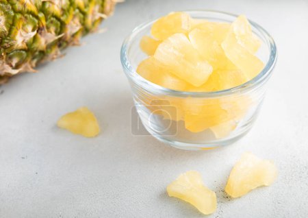 Photo for Dried soft sweet pineapple slices in glass bowl with raw pineapple on light table.Macro - Royalty Free Image