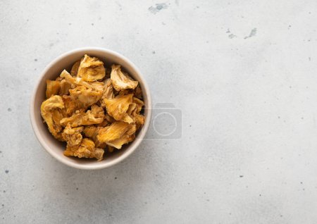 Photo for Dried pineapple slices chips in glass bowl on light background. - Royalty Free Image