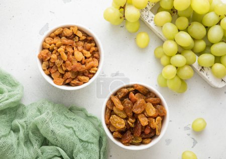 Téléchargez les photos : Raisins secs verts doux avec des raisins crus mûrs sur fond clair. - en image libre de droit