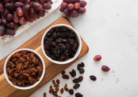 Téléchargez les photos : Deux bols avec des raisins secs avec des raisins rouges mûrs sur fond clair. - en image libre de droit