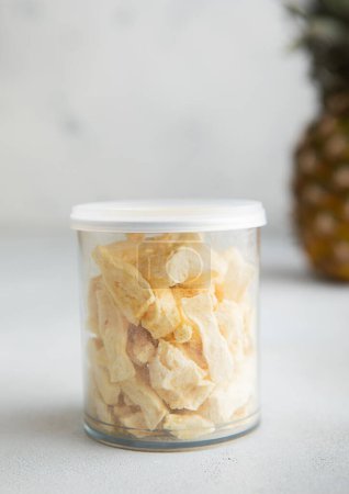 Photo for Plastic jar of freeze dried pineapple slices on light table.Macro - Royalty Free Image