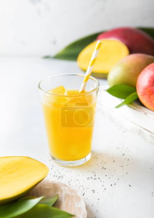 Foto de Zumo de mango fresco y vaso con cubitos de hielo y frutas frescas crudas. - Imagen libre de derechos