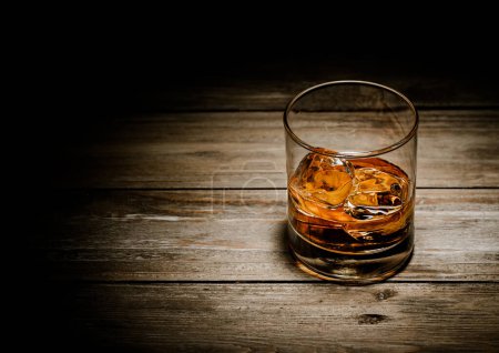 Foto de Cristal de whisky clásico con cubitos de hielo sobre fondo de madera.Vista superior. - Imagen libre de derechos