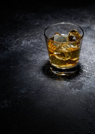 Téléchargez les photos : Verre à whisky avec glaçons au milieu du fond noir.Macro - en image libre de droit