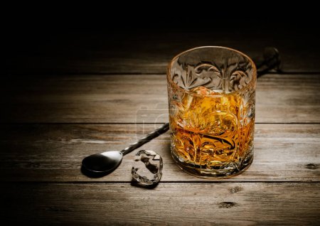 Téléchargez les photos : Verre de whisky single malt avec cuillère de bar et glaçons sur planche en bois. - en image libre de droit