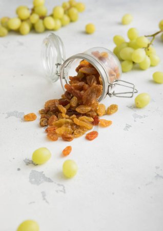 Téléchargez les photos : Raisins secs verts dans un bocal en verre sur fond clair. - en image libre de droit