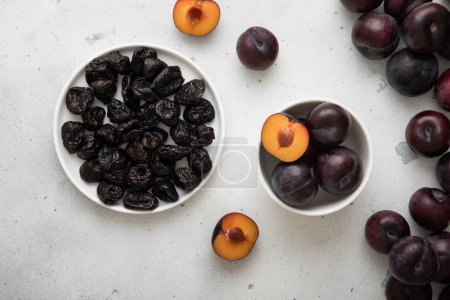 Photo for Dried prunes and ripe raw plums on light background. - Royalty Free Image