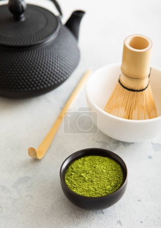Foto de Hervidor de hierro japonés con polvo de té verde matcha con cuchara de bambú y batidor en tazón de cerámica en blanco. - Imagen libre de derechos
