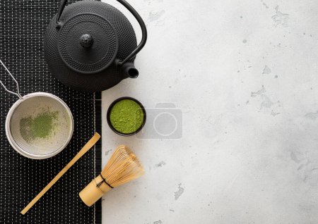 Foto de Hervidor de hierro japonés con polvo de té verde matcha con batidor y cuchara y tazón con tamizador sobre fondo blanco. - Imagen libre de derechos