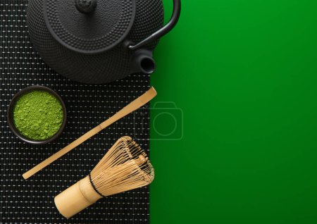 Photo for Organic matcha green tea powder with bamboo whisk and spoon and japanese traditional iron cast kettle on green background. - Royalty Free Image