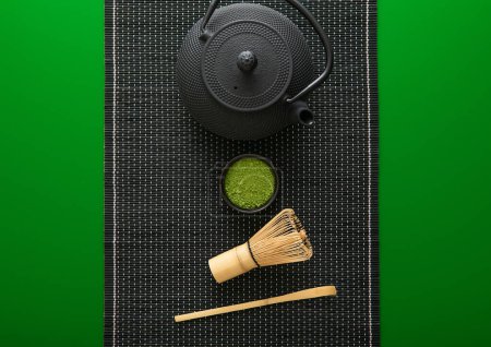 Téléchargez les photos : Poudre de thé vert matcha biologique avec fouet en bambou et cuillère et bouilloire traditionnelle japonaise en fonte sur fond vert. - en image libre de droit