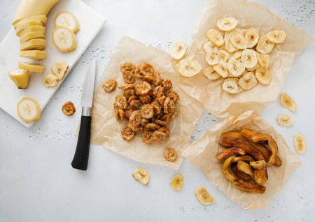 Foto de Chewy y crujientes rodajas de plátano y patatas fritas snack con plátano crudo y cuchillo.Vista superior. - Imagen libre de derechos