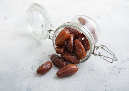 Photo for Glass jar with brown sweet dried dates on white kitchen background. - Royalty Free Image