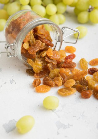 Téléchargez les photos : Raisins secs verts dans un bocal en verre sur fond clair.Macro - en image libre de droit